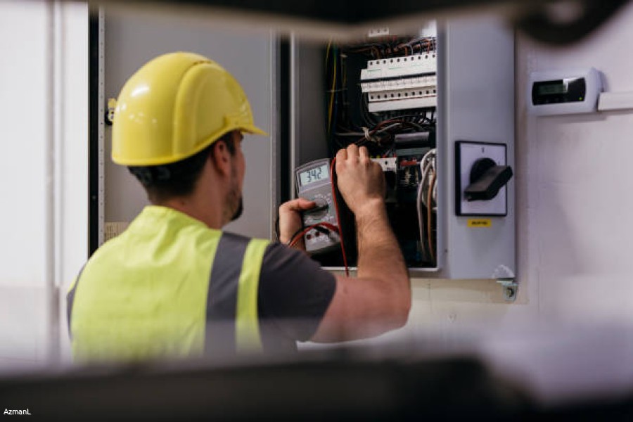 Manual worker is checking the electricity in a production hall.
